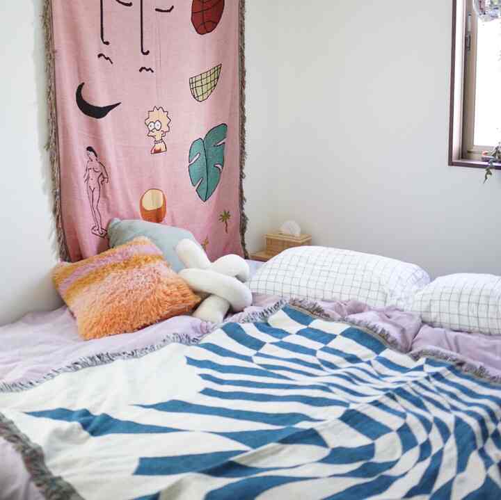 白い壁とライトグレー、青のパターンが配置されたベッドルーム、クッションと枕があり、落ち着いた雰囲気のあるインテリア