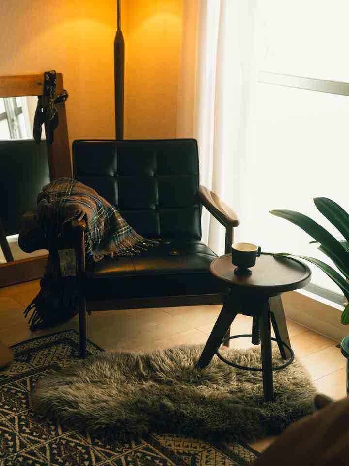 Cozy reading nook with warm lighting and natural wood tones, featuring a black K Chair and fluffy rug