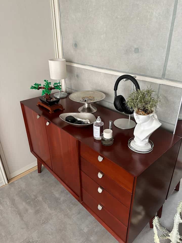 ブラウンの木目調キャビネットに多様なオブジェや植物が並ぶ落ち着いたインテリア