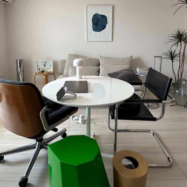 White and beige toned living room combined with home office, featuring central round table and chairs in a cozy atmosphere