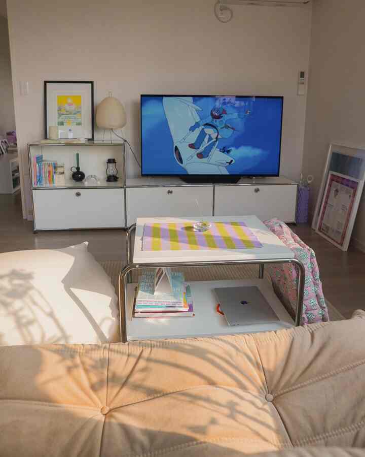 温かみのあるベージュと白の色調のリビング、ミニマルなソファとテレビ台、サイドテーブルが配置された落ち着いた空間