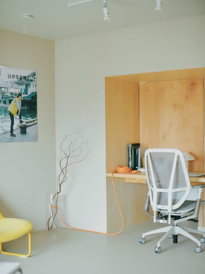 White and yellow toned home office space featuring a desk and office chair with a natural, minimal atmosphere