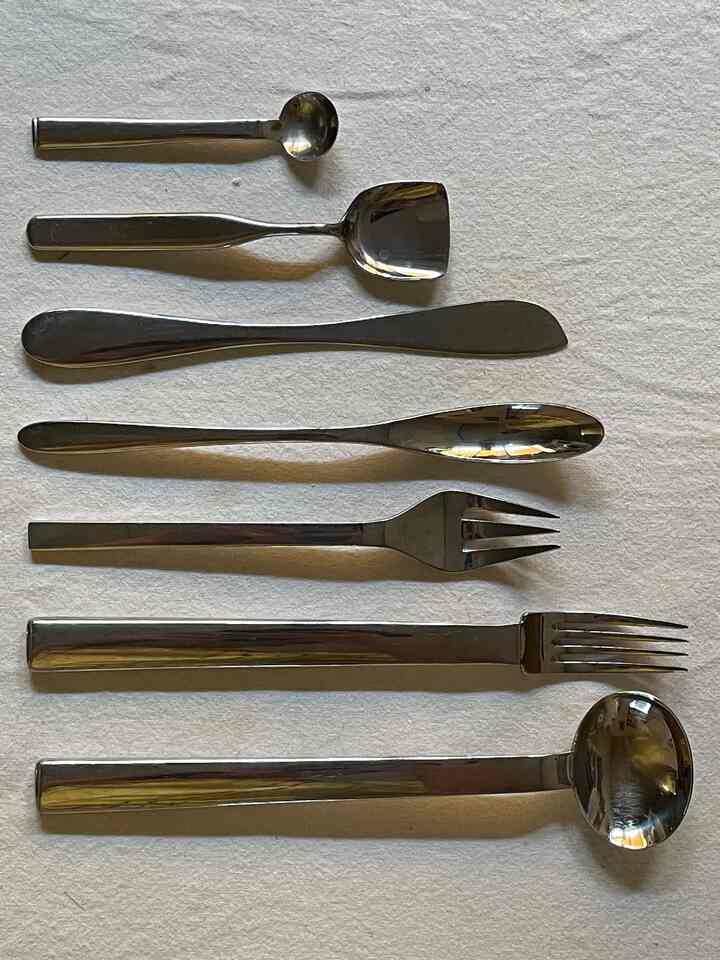 銀色のステンレス製カトラリーが白い背景に整然と並べられたキッチン用品の画像