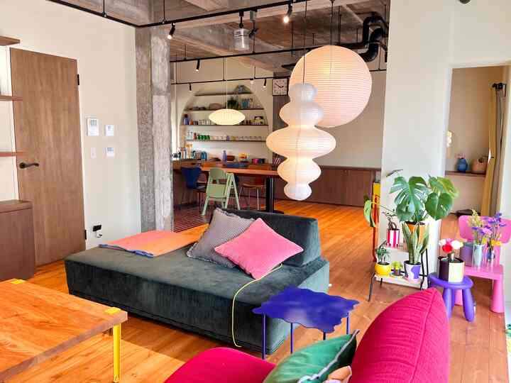 Natural wood-toned mid-century modern living room with colorful cushions and distinctive pendant lamps