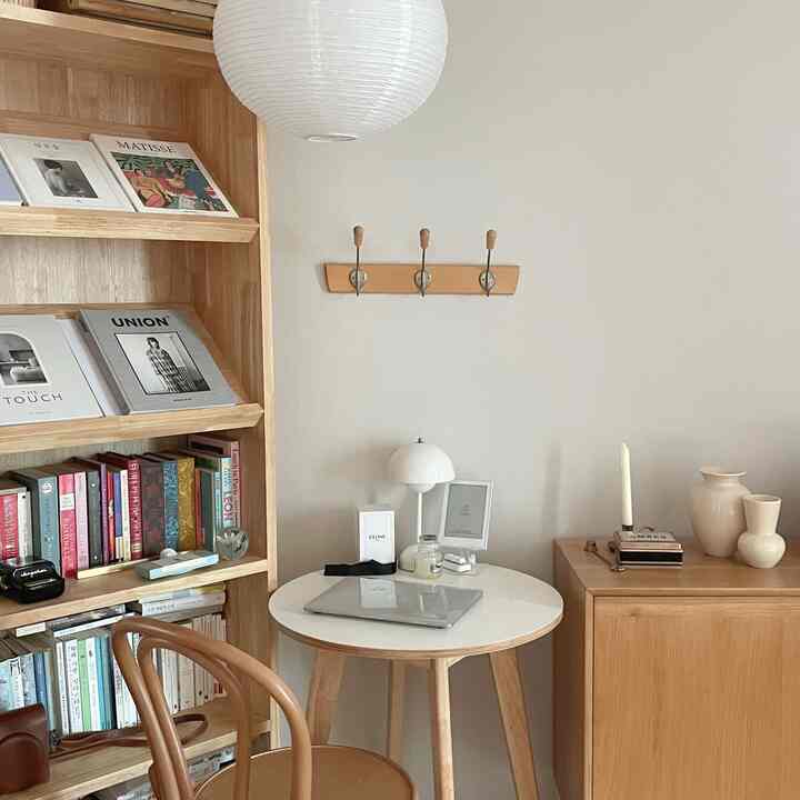 ホワイトと木目調が調和したコンパクトな寝室、小さな丸テーブルと本棚が配置された雰囲気のあるインテリア