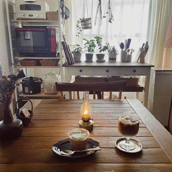 ブラウンの木目調のダイニングテーブルと白いコンソールテーブル、植物が配置されたナチュラルでレトロな雰囲気のあるおうちカフェ空間