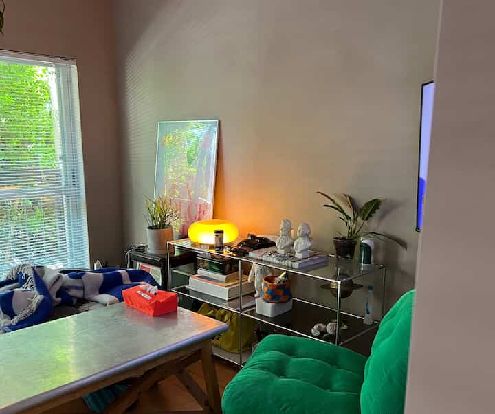 ナチュラルな色調とグリーンのアームチェアが配置された居心地の良いリビング、サイドテーブルと多様な装飾品で印象的な空間