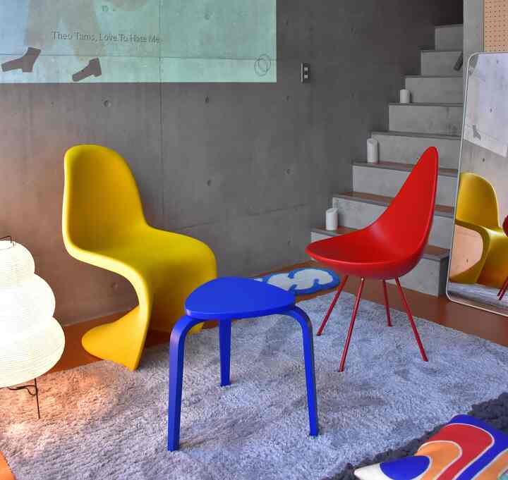 Mid-Century Modern living room in red, yellow, and blue featuring uniquely designed chairs and a stool in a cozy setting