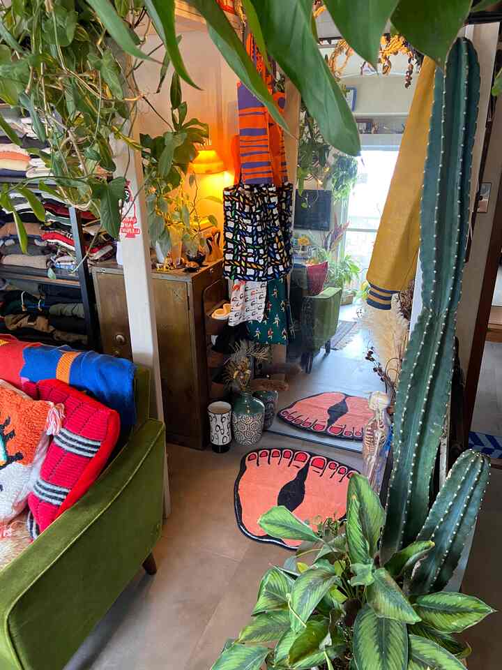 緑色のソファと多彩な足跡型ラグ、多数の観葉植物が配されたヴィンテージ風昭和レトロのリビングスペース