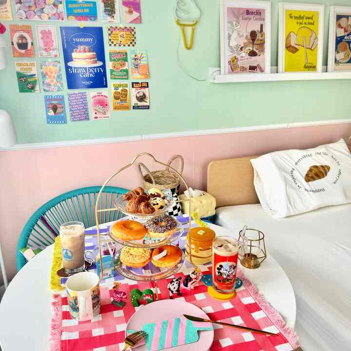 ピンクとミントの色調の寝室、ダイニングテーブルに様々なデザートとドリンクが置かれた雰囲気のあるカフェ風インテリア