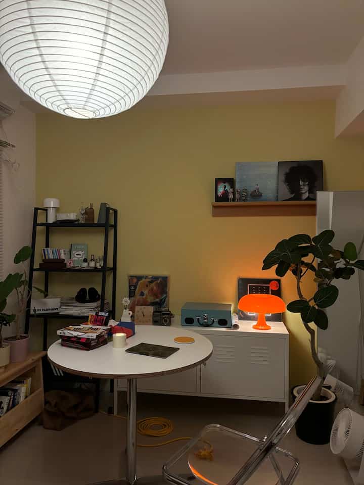 黄色い壁と白い家具、テーブルランプが配置された雰囲気のあるリビング