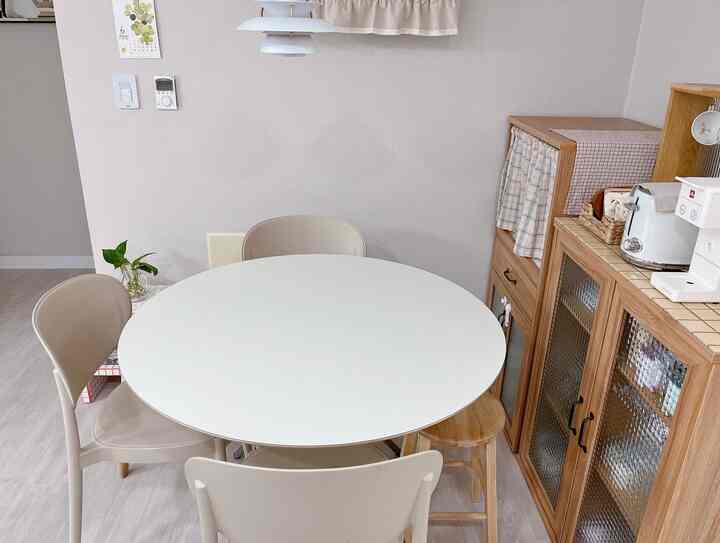 白とナチュラルな木目調のダイニングテーブルと収納棚が配置された、落ち着いた雰囲気のキッチン空間