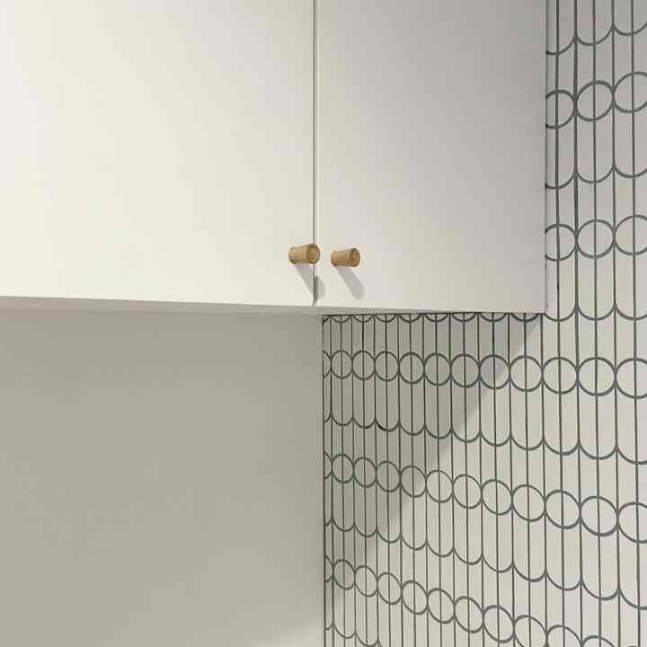 白い壁とコーナーに設置された白いキャビネットが調和するミニマルなキッチン収納空間