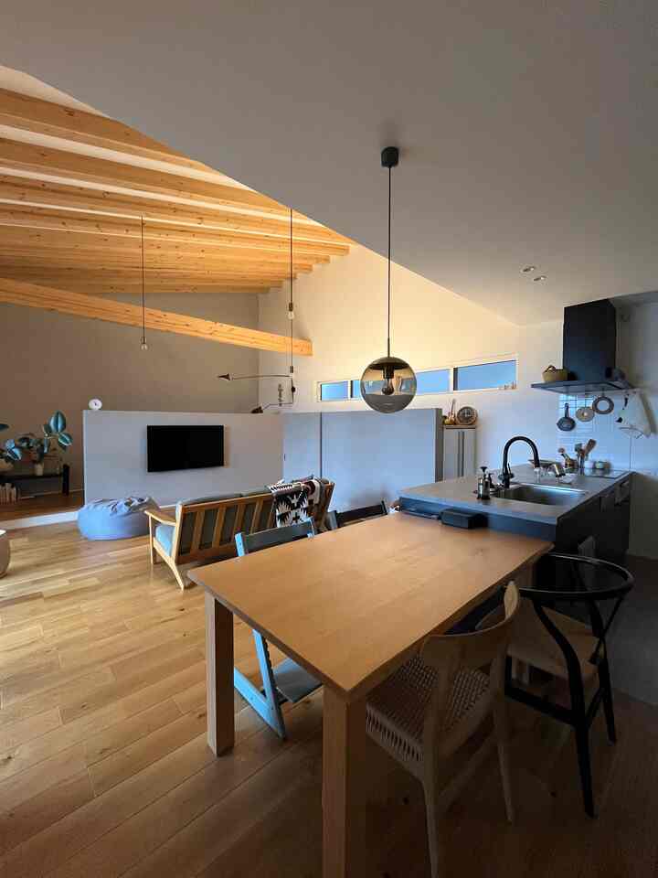 ウッドトーンと白い壁の16畳のリビング・ダイニング、異なる椅子とソファが配された温かみのある空間