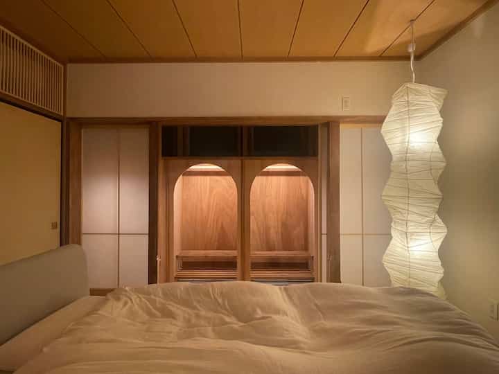 Warm brown and white toned Japanese renovated master bedroom featuring an arch-shaped built-in closet as a focal point