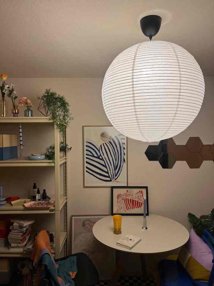 ライトグレーの色調のダイニングルーム、丸いダイニングテーブルと大きな和紙のペンダントライトが配置されたシンプルでアートな空間