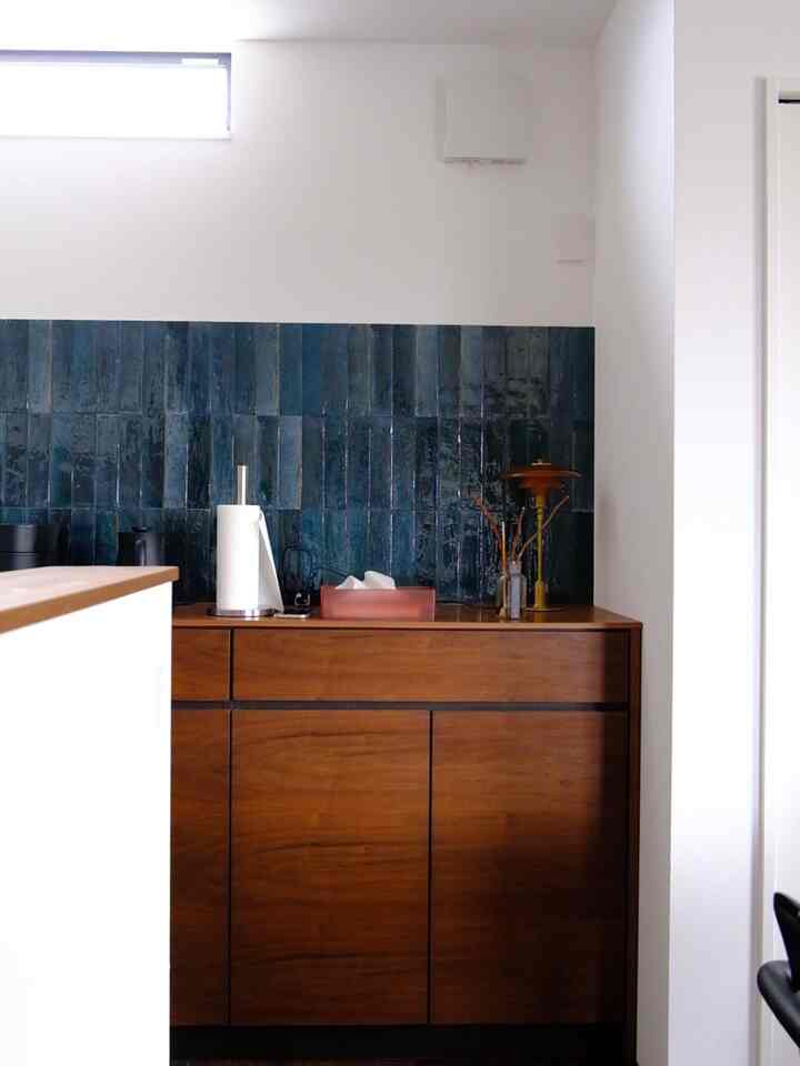 ナチュラルブラウンのチェストとブルーのタイルが調和するモダンなキッチンスペース