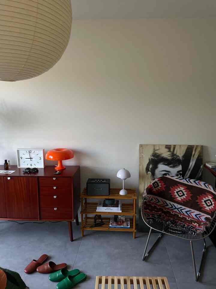 Simple Nordic living room with warm brown wood tones and orange accents, featuring a wooden bench and framed clock on the wall