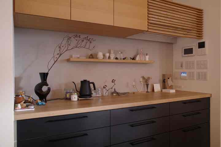ウッドトーンとブラックの組み合わせのキッチン、電気ポットや小物が棚とカウンターに配置されたカフェ風の雰囲気のあるインテリア