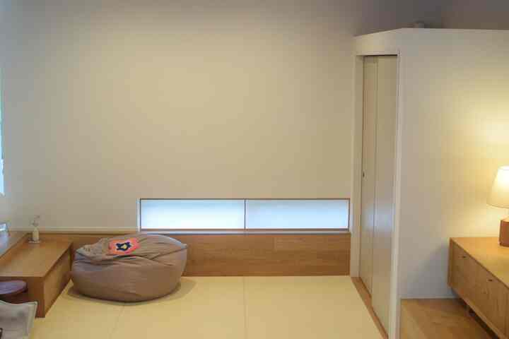 ベージュの畳とビーズクッションが配置された、木目調と白い壁のピットリビングコーナーの空間