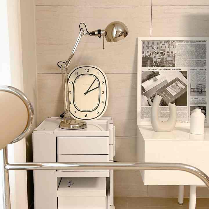 白とベージュのトーンのコンパクトな空間、クロームのテーブルランプとモダンな収納が配置された清潔感のあるインテリア