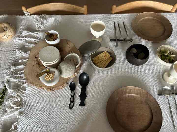 ナチュラルなブラウンとホワイトのトーンのダイニングテーブル、木製の皿と洗練された食器が配置された雰囲気のあるインテリア