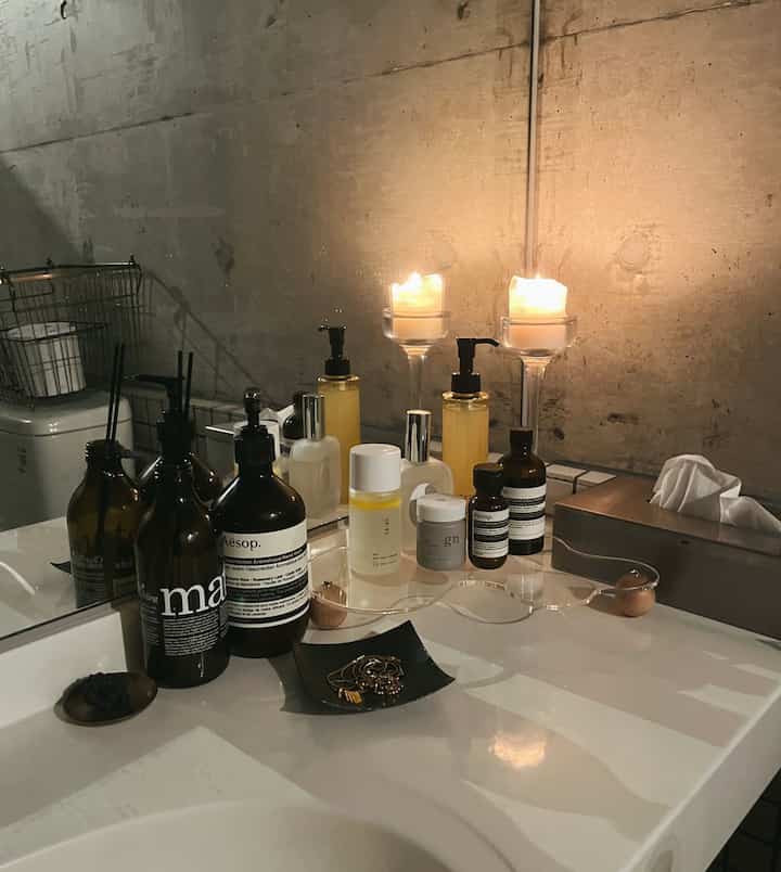 Natural tones blend with white in a bathroom powder room featuring an acrylic tray, candles, and neat warm ambiance
