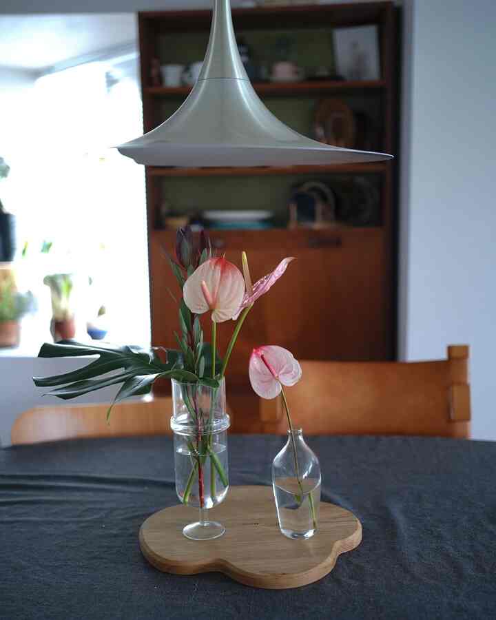 木目調とグリーンが調和したダイニングテーブル、花瓶とトレイが配置された雰囲気のあるインテリア