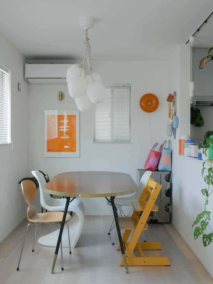 白を基調としたダイニング空間、黄色のハイチェアとダイニングチェアが配置され、モダンなペンダントライトが特徴的な雰囲気のあるインテリア