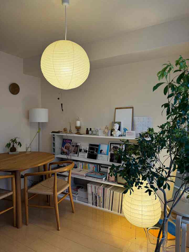 Natural color tone living room featuring a round wooden dining table, Japanese AKARI pendant and floor lamps creating a warm atmosphere