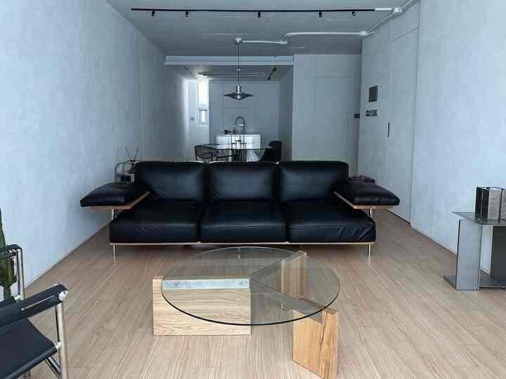 ウッドトーンの床とブラックレザーソファが配された、モダンなインダストリアルスタイルのリビングルーム