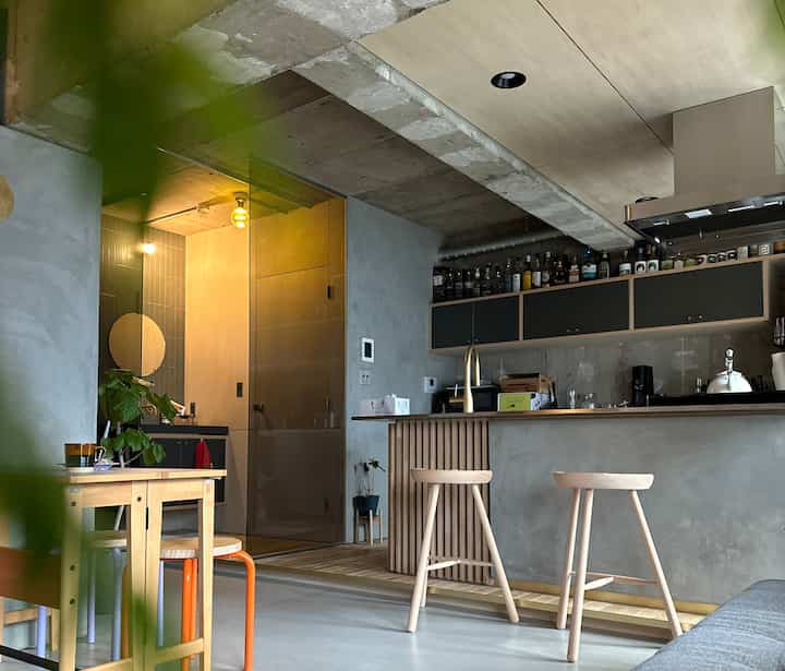 Gray and wood-tone modern living room and kitchen space featuring bar stools and warm lighting with cozy atmosphere