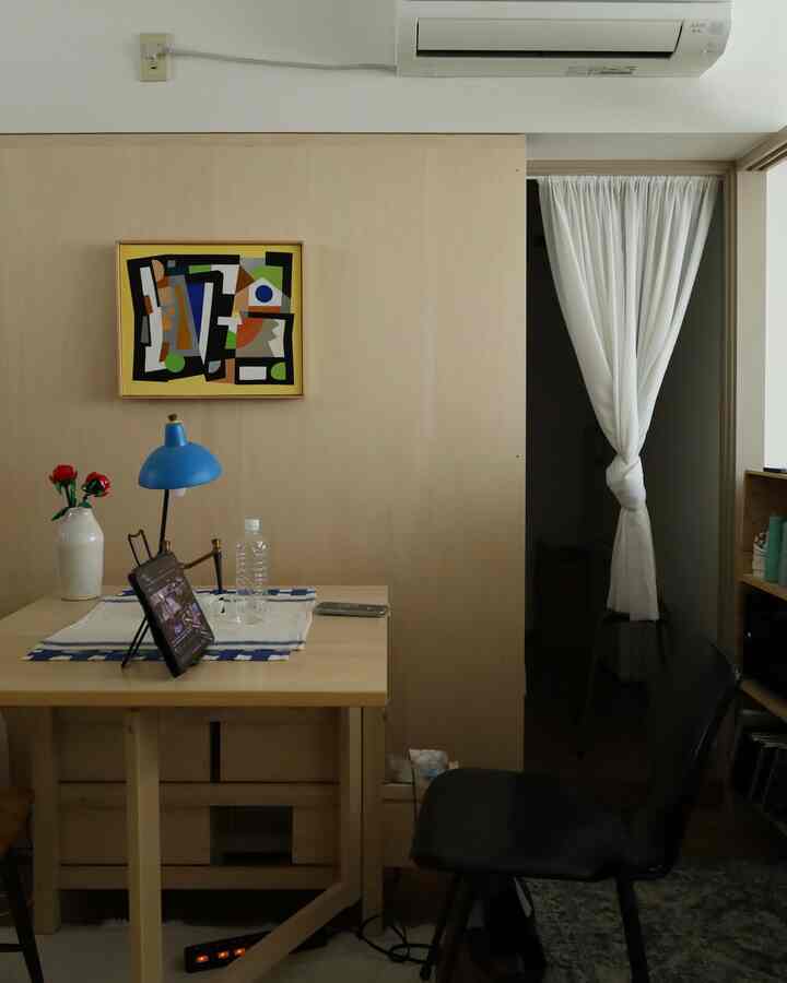 Wood tone and white background single-person dining room with multifunctional table, chair, and blue table lamp creating a cozy atmosphere