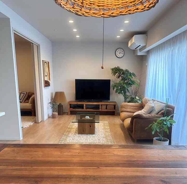 ナチュラルカラーのリビング、ブラウンのソファと木製テレビ台が配置された落ち着いた空間