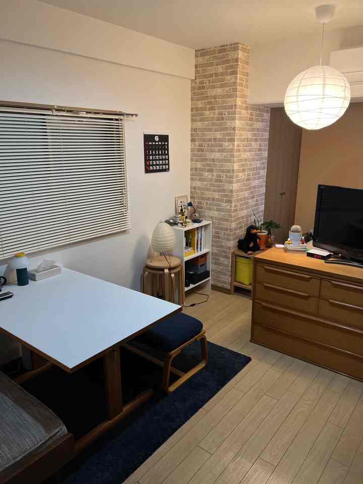 木目調とネイビーが調和した居心地の良いリビング兼ダイニング、レンガ柄の壁と和紙ランプが配されたシンプルな空間