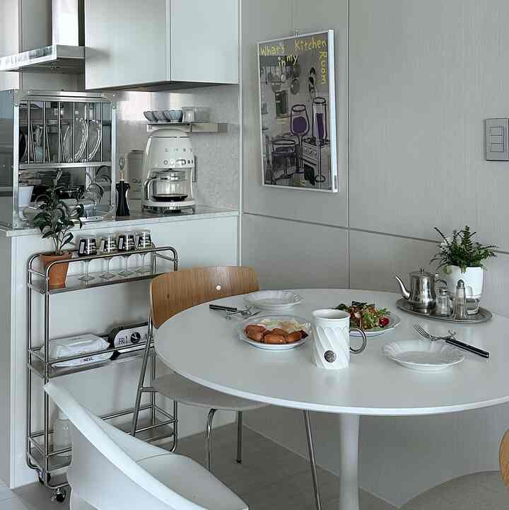 白を基調としたキッチン空間、丸いダイニングテーブルとミッドセンチュリーモダンチェアが配置された落ち着いた朝食の雰囲気のあるインテリア