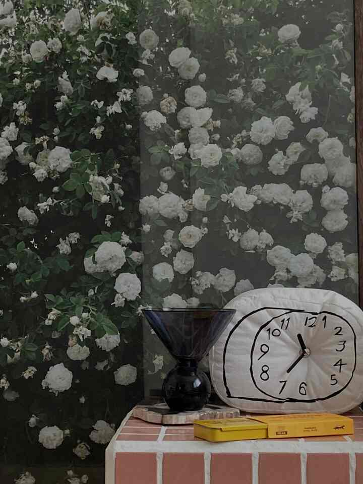 白と茶色のトーンの寝室、タイルテーブルとインセンス、アート時計が配置されたミッドセンチュリーモダンなインテリア