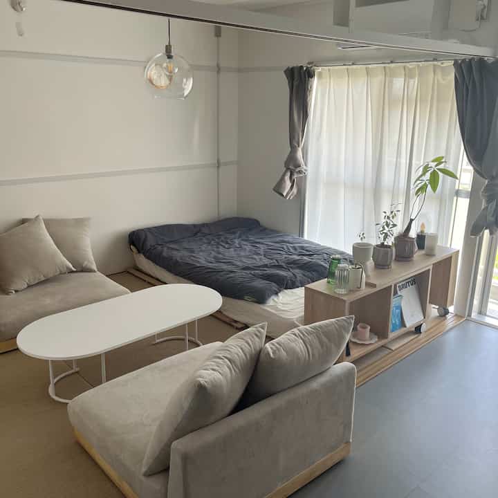 Beige and gray toned studio living room featuring low simple two-person sofas, coffee table, and floor bed in a natural modern style