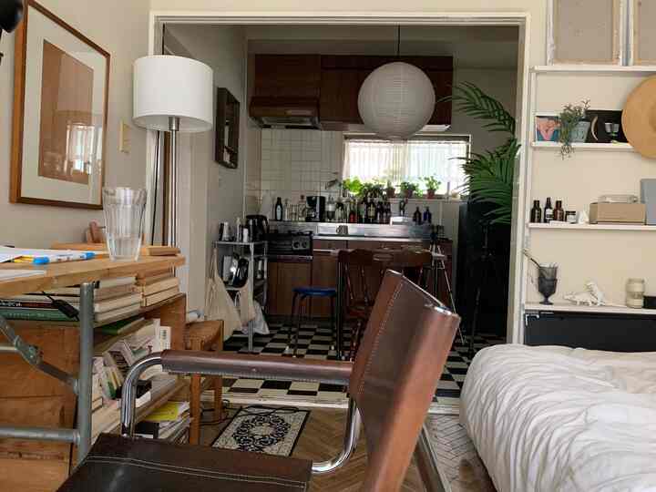 A cozy studio apartment featuring brown wood tones and white elements, blending kitchen and bedroom spaces naturally