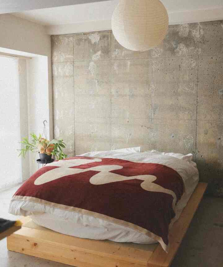 Natural color and red bedroom featuring wooden platform bed and mattress with pendant light and plant