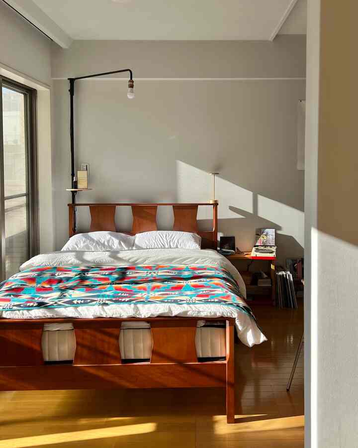 Natural brown and white toned bedroom featuring wooden bed and white bedding with warm sunlight atmosphere