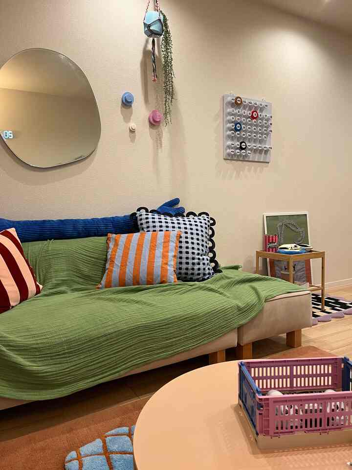 Natural color toned living room featuring a beige sofa with green cover, colorful cushions, and a small side table creating a cozy atmosphere