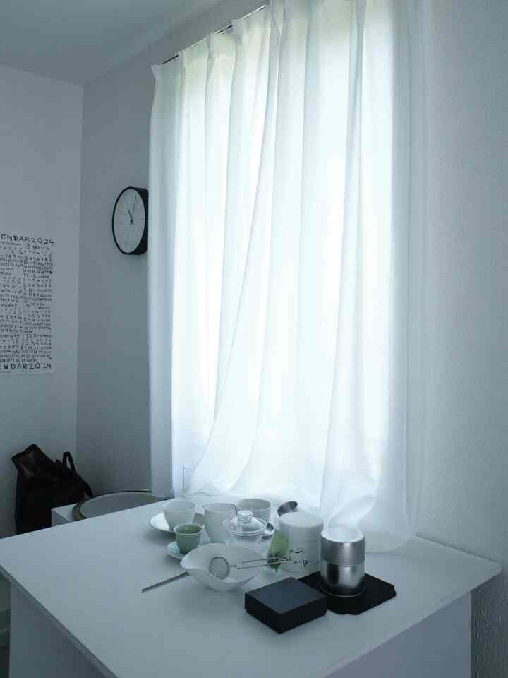 White-toned small space featuring sheer white curtains and a teacup set on a minimalist home cafe corner with cozy atmosphere