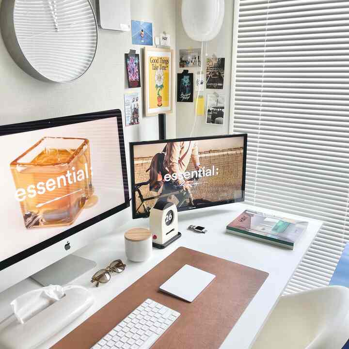 白を基調とした清潔感あるワークスペース、デュアルモニターとブラウンのフェイクレザーマットが配置されたミニマルなインテリア