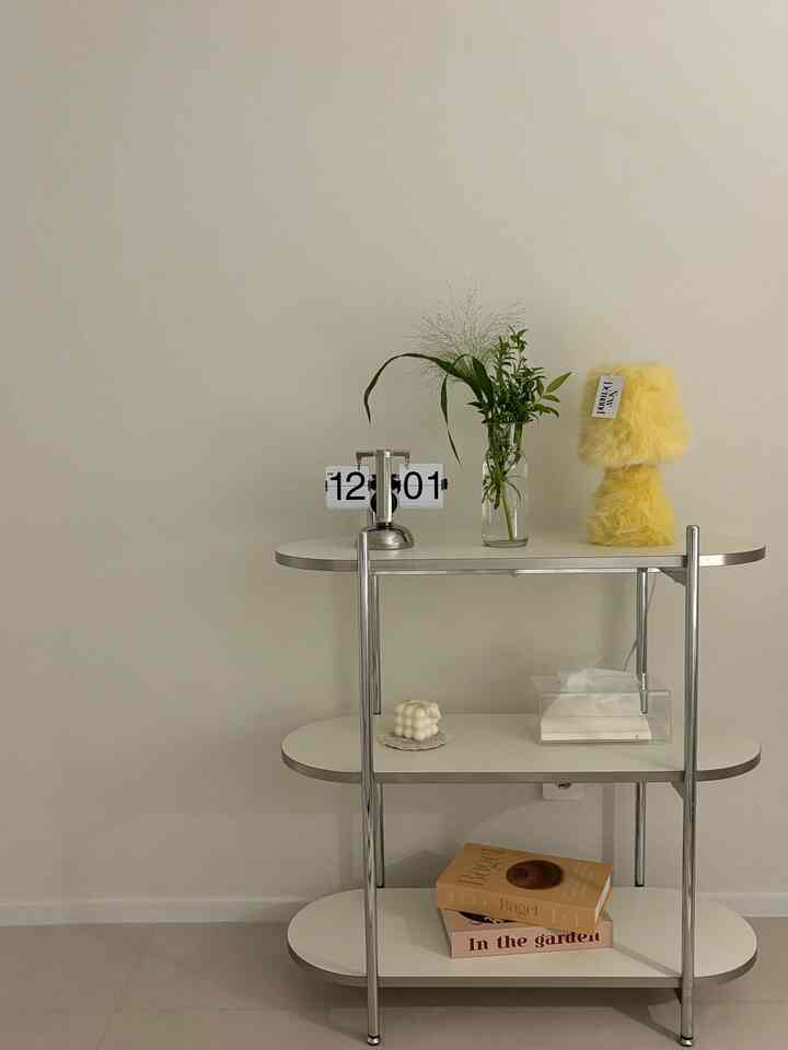 ホワイトトーンのシンプルモダンなサイドテーブルにレトロなフリップクロックと黄色いテーブルランプが配置されたインテリア小物のある空間