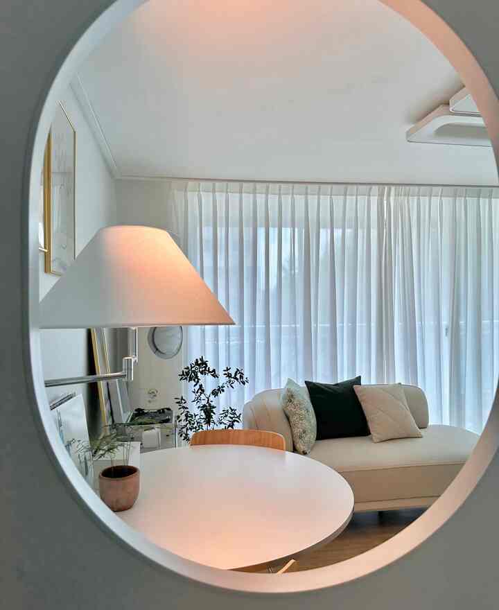 ホワイトとウッドトーンが調和したシンプルで自然なリビング、円形テーブルとソファが配置され落ち着いた雰囲気のあるインテリア