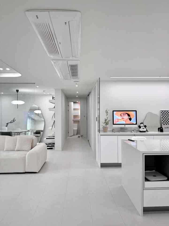 ホワイトとグレーのトーンのリビングルームとホームオフィス、モダンなソファとデスクが配置された清潔感あるインテリア