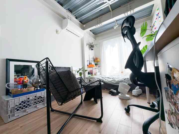 White-walled, wood-toned studio apartment featuring Mid-Century Modern furniture and ergonomic office chair with cozy atmosphere