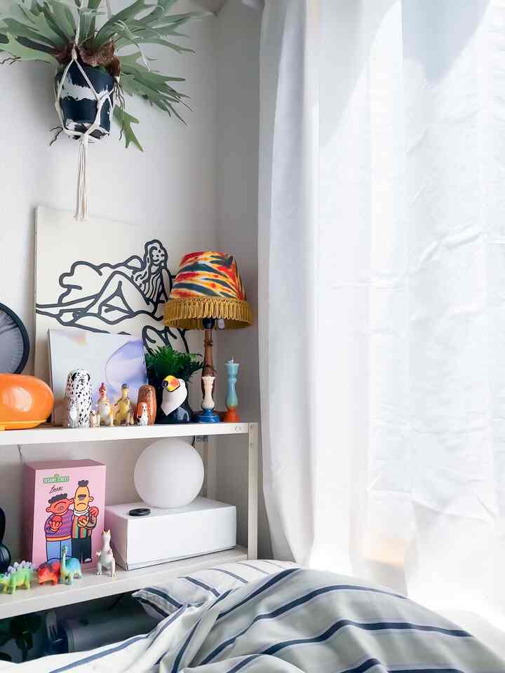 白を基調とした6畳ワンルーム、ミッドセンチュリーモダンの小物とウォールアート、カラフルなテーブルランプが配置された雰囲気のあるインテリア