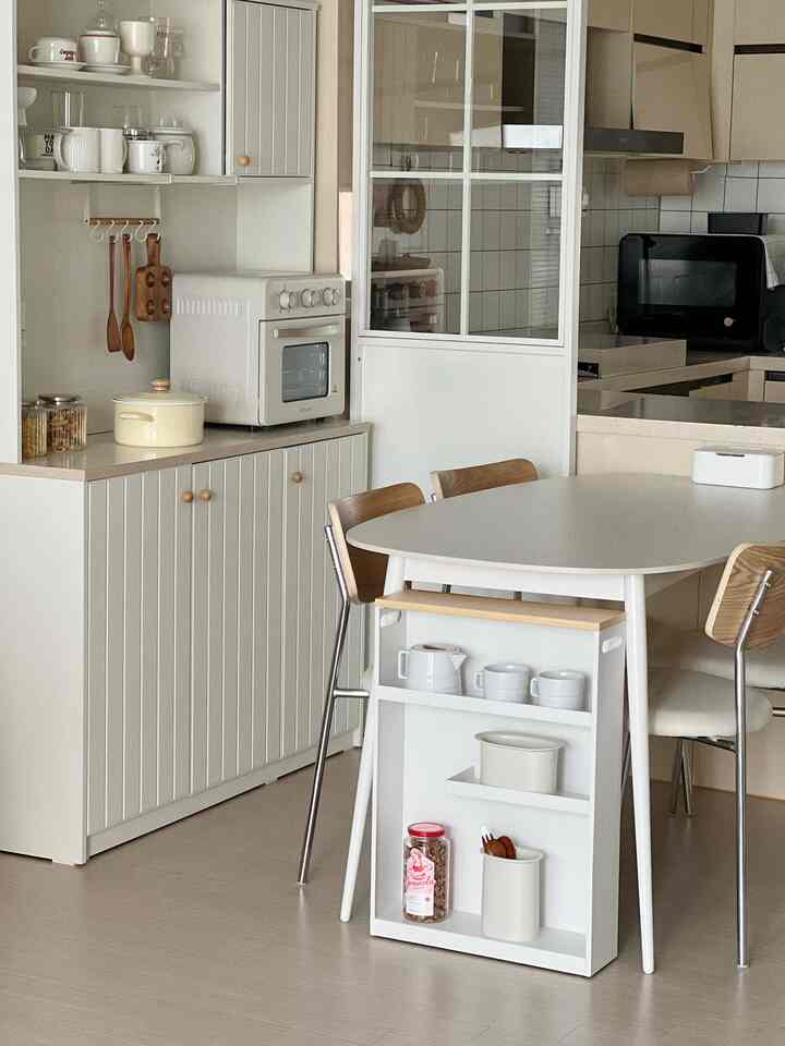 Beige and white toned kitchen with dining table and wood-tone chairs in a clean and natural kitchen space